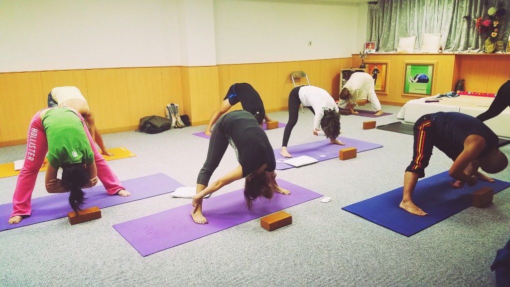 Students in a supported wide-legged forward fold during class at LMYC