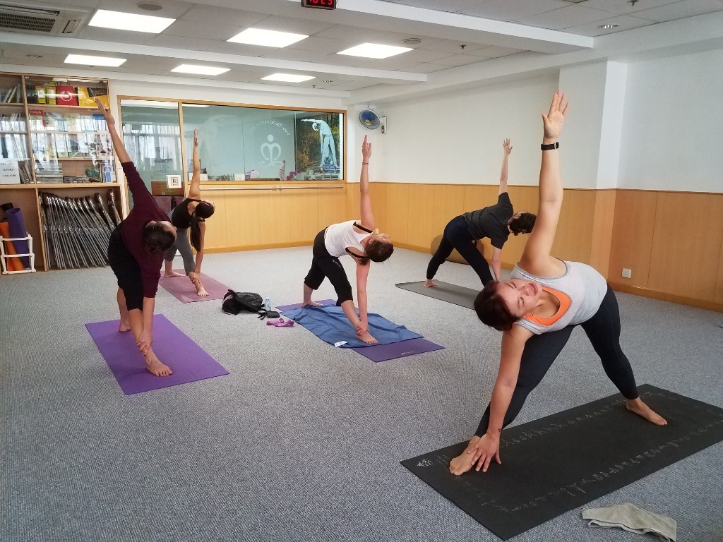 Women practising triangle pose together in the LMYC main studio